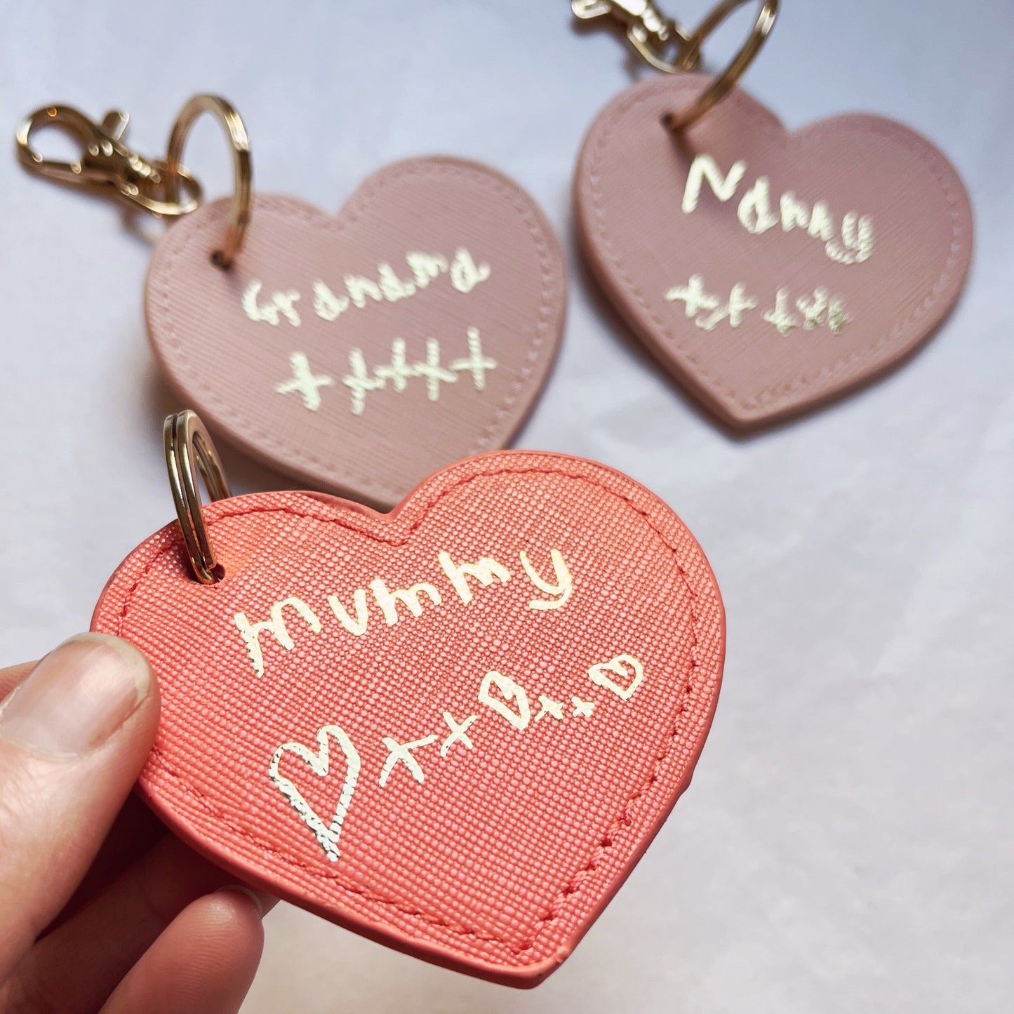 Heart-shaped keychains with 'Mummy' and 'Grandad' text on a light background