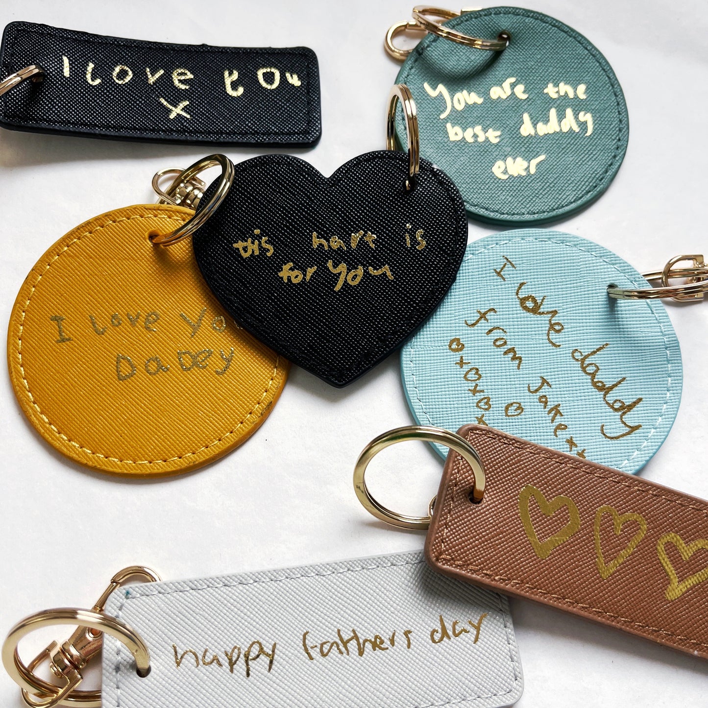 Collection of personalized keychains with handwritten messages on a white background
